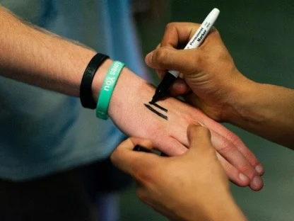 Someone drawing the three tally marks onto another person’s hand