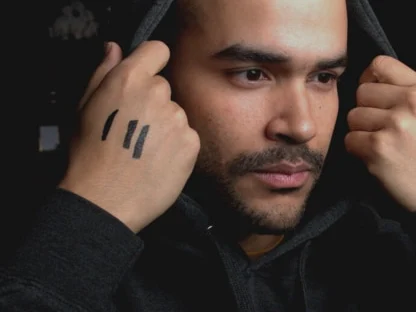A young man in a hooded top, marks drawn across his hand