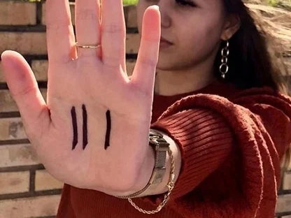 A woman holding up an open palm marked with three lines