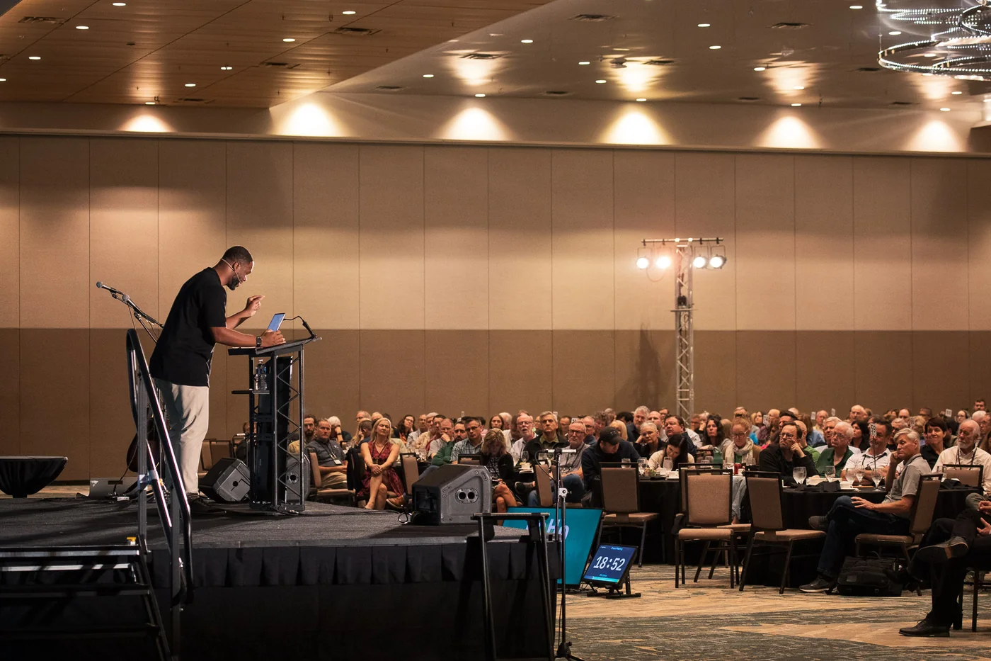 A speaker at a lectern addressing a seated audience at a regional event