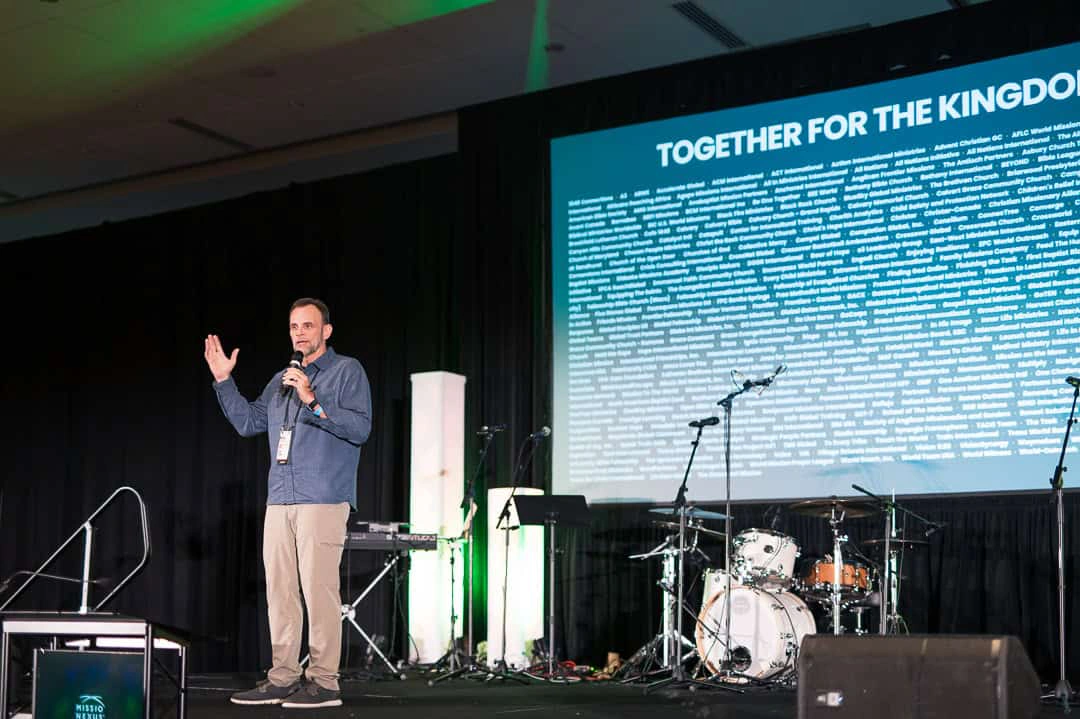 A speaker on the main stage under a Together for the Kingdom screen