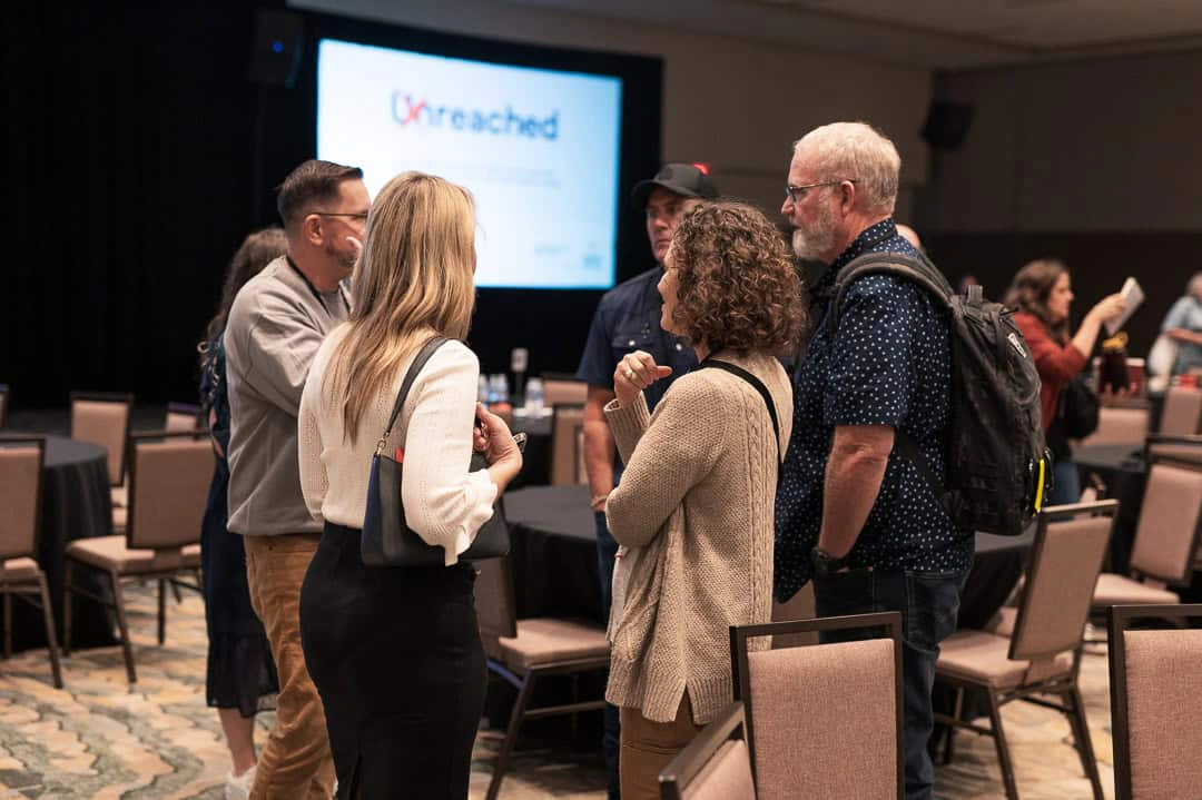 Attendees talking in a group in the ballroom between sessions