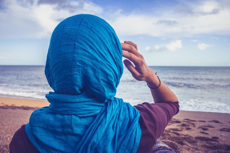 Rear view of woman with headscarf looking at the sea