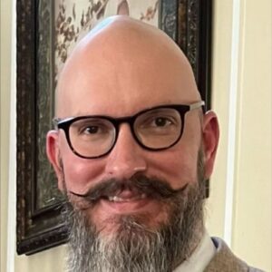 Close-up of a smiling man with glasses and a beard at THE NEXUS Cincinnati event.