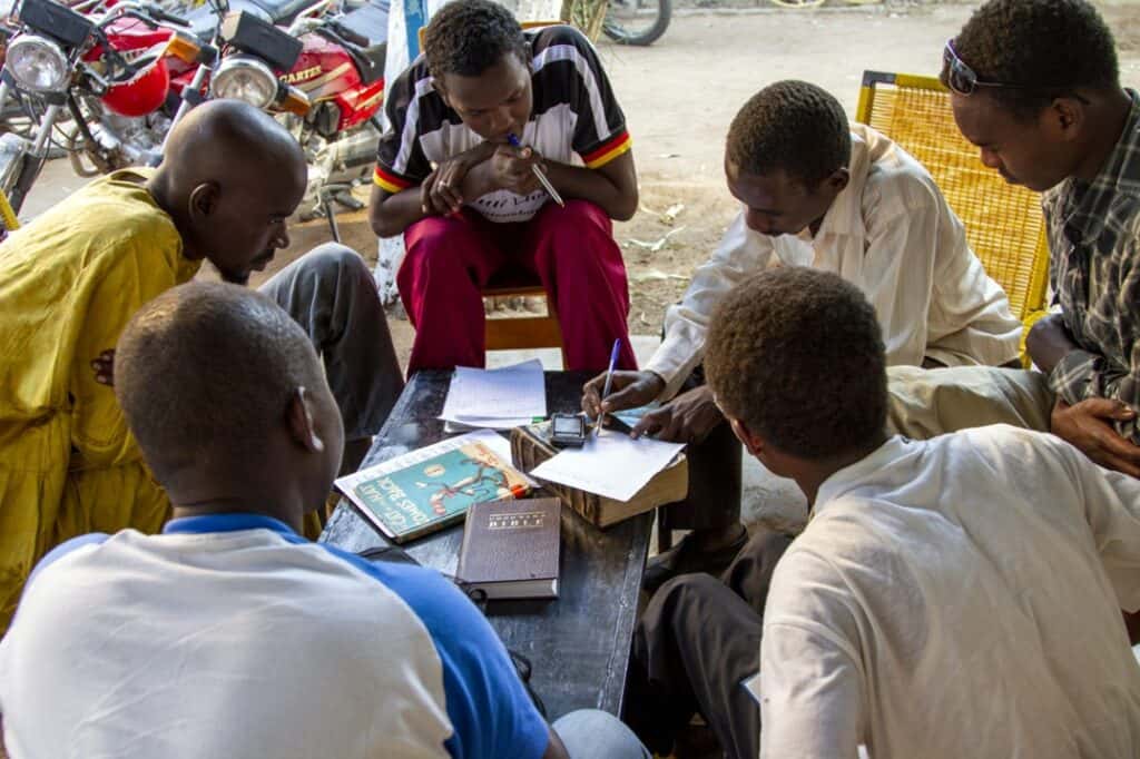 Group of African church members engaging in community discussion outdoors.