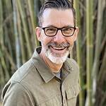 Smiling man with glasses and beard outdoors, representing Missio Nexus.