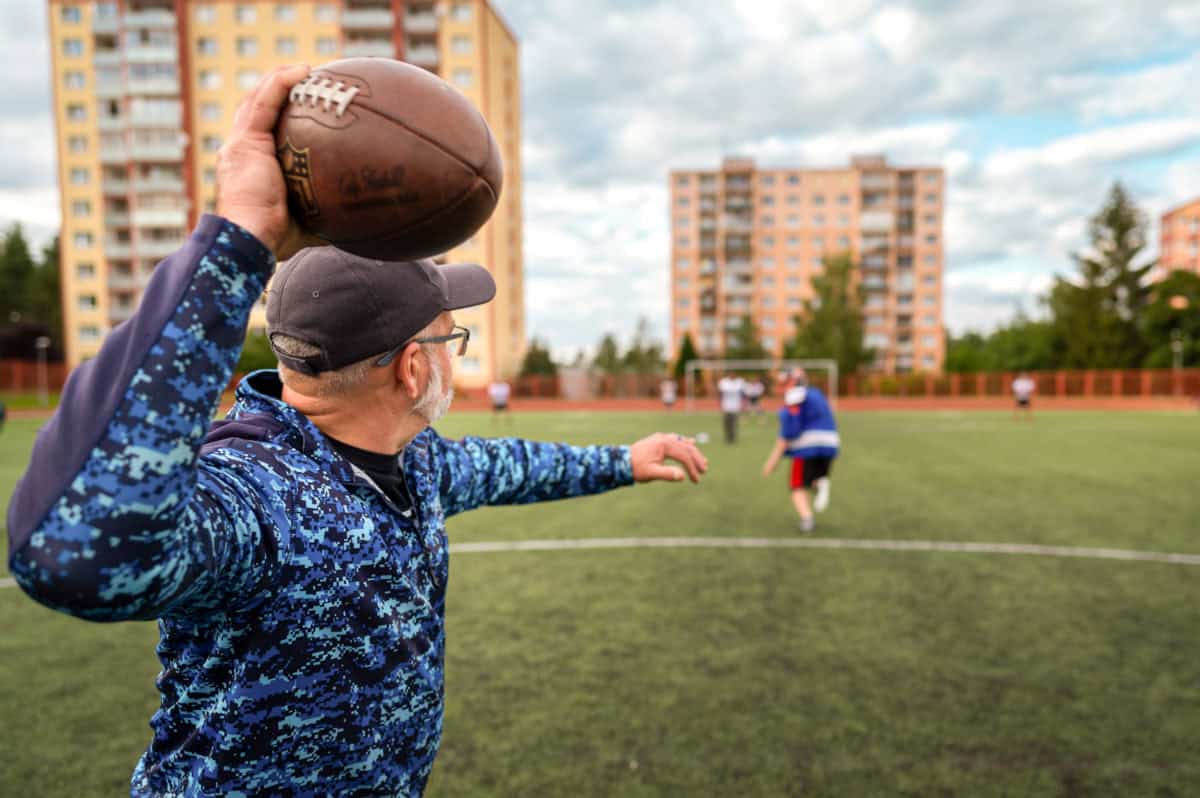 Man throwing football on field during game, illustrating faith and community engagement.