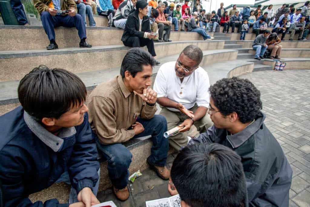 Missionaries and community members having a discussion on steps of an outdoor amphitheater.