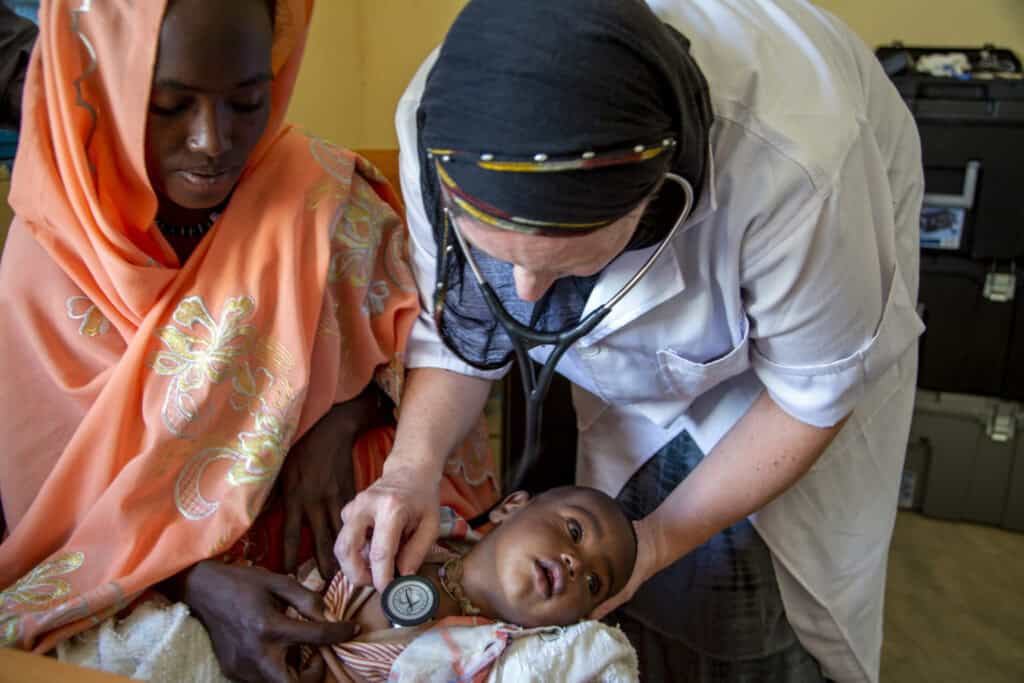 Medical healthcare worker examining a young child in a clinical setting.