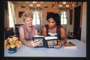 Two women looking at photo albums at a table in a cozy room.