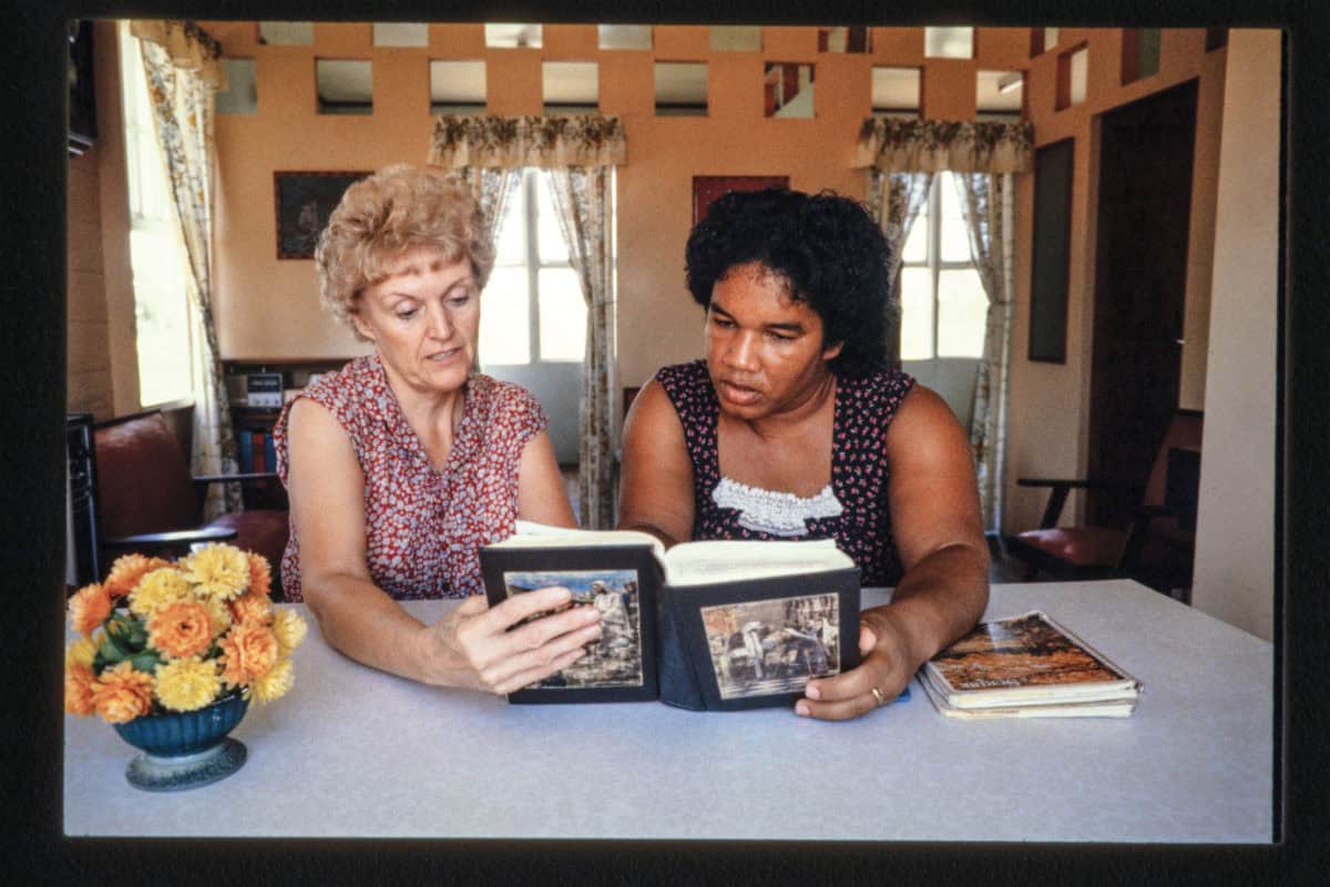 Two women looking at photo albums at a table in a cozy room.