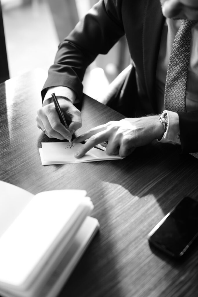 Business professional writing notes at a desk, Mission Nexus Resources & Support Hub.