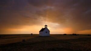A church building at sunset with dramatic sky and open landscape.