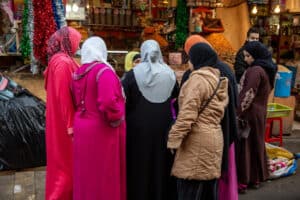 Group of women in colorful traditional clothing shopping at a market.