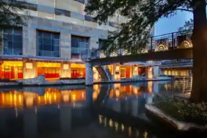 Modern hotel with a canal and illuminated walkways at dusk.